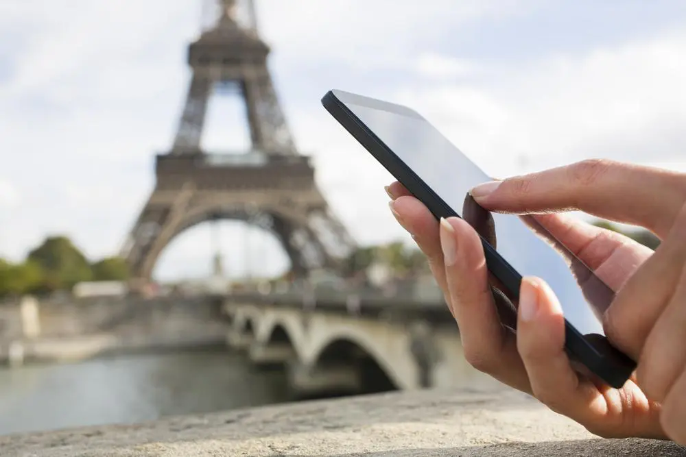 Australia ranks 14th globally for traveller-friendly internet but best in region 2 Hand with smarphone in Paris with Eiffel Tower and River Seine in background. Image: Shutterstock
