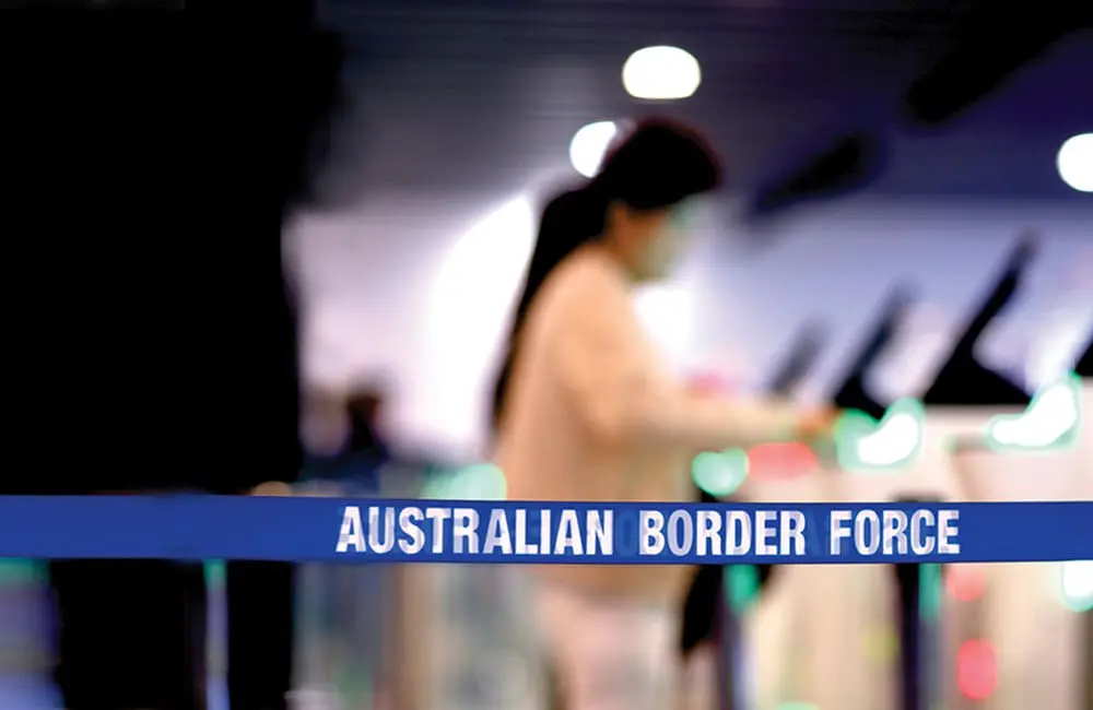 Blurred image of passenger at SmartGate with Australian Border Force on tape.