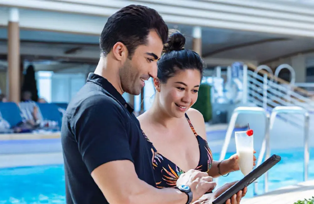 Princess Cruises goes overboard with 3 new all-inclusive Princess Premier unlimited features 2 Passengers with tablet near pool using MedallionNet Max Wi-Fi as part of the Princess Premier package.