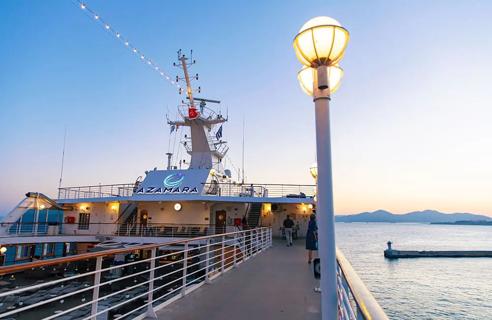 Passengers on the pool deck of an Azamara Cruises ship at sunset at sea.