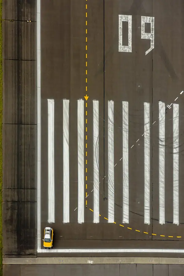 Safety vehicle inspecting Melbourne Airport runway, aerial shot.