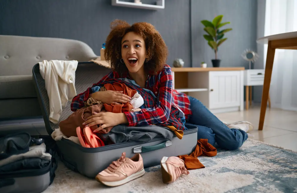 Happy woman with overflowing suitcase.