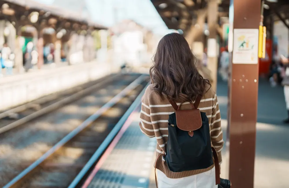 Make a Japan train holiday rail-ly easy for your clients with JR-East Hotels 9 Female traveller waiting for train at Kamakura Station in Kanagawa, Japan.