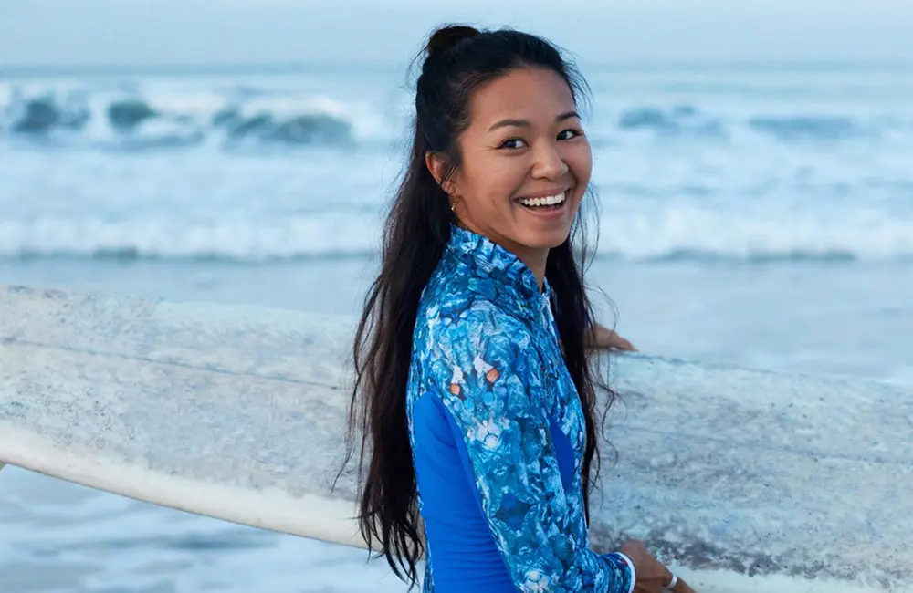High flyers: 72% of APAC travellers plan to spend more or the same on flights in 2025 4 Smiling female surfer with board – Skyscanner Horizons 2025 Report