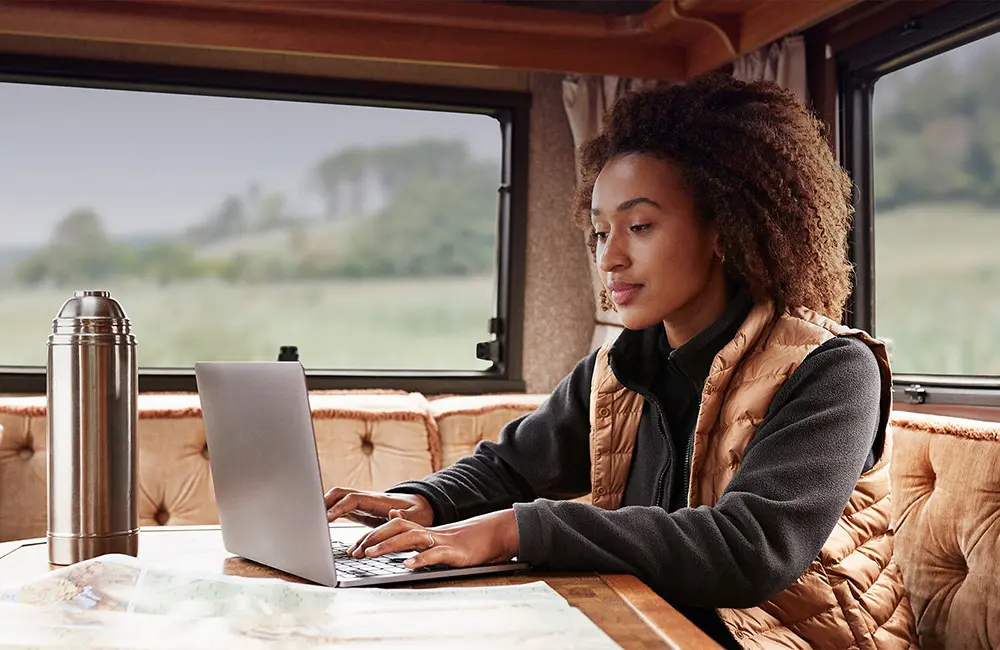 Woman in caravan searching flights on laptop for Skyscanner Horizons 2025 Report.