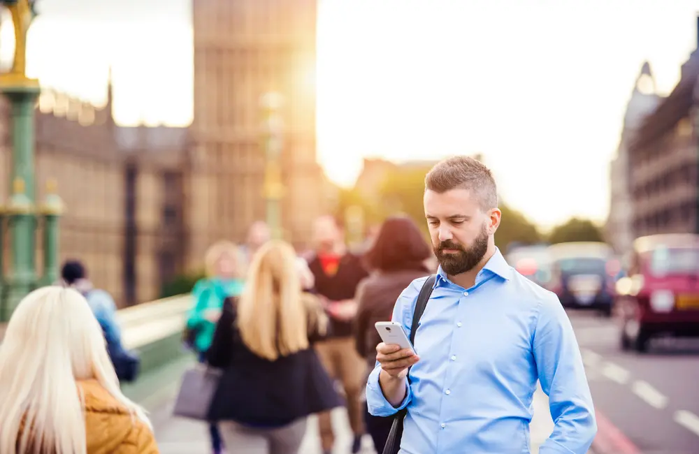 “This isn’t a farewell”: Spencer Travel sells corporate arm after 26 years, pivots to leisure 2 Male business traveller looking at smartphone on busy Westminster Bridge in London, UK