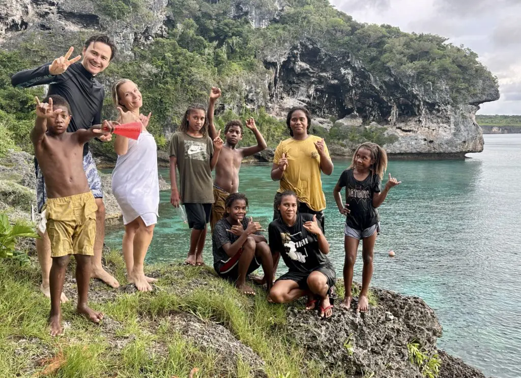 Govt changes travel advice level for holiday destination on Australia's doorstep 2 Mark (second from left), Rebecca (third from left) enjoying Lifou with some local kids.
travel advice