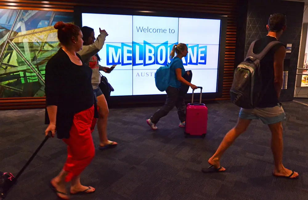 Traveller tax reform: How better PMC use could improve Australian airports 3 Travellers walk past Melbourne sign at Melbourne Airport
