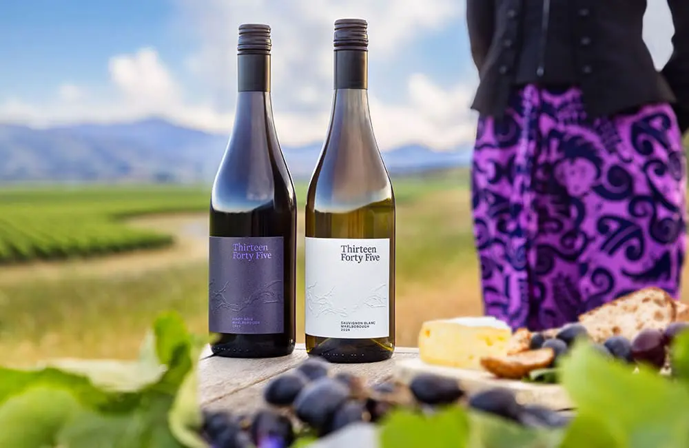 Cheers to 85 years! Air New Zealand debuts wine label exclusively for flyers and members 2 Air New Zealand's Thirteen Forty Five wine bottles with female flight attendant and Marlborough region in background.