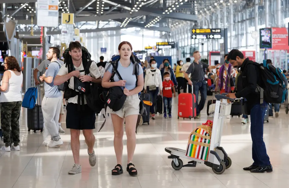 Has the death of Thailand’s Queen Mother Sirikit impacted travel? What Aussies need to know 2 Young male and female tourists in busy Bangkok Suvarnabhumi Airport.