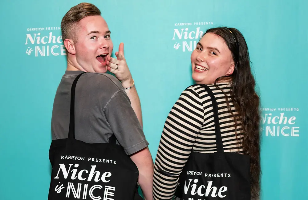 12 Years ‘Together in Travel’: A thank you from Karryon 5 Male and female travel agents at industry event with bag in front of branded wall that says: Karryon Presents Niche is Nice.