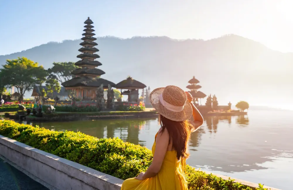 Missing the points: Are you sitting on $3,000 in free travel? Most Aussies don’t even know it 2 Woman admiring the view at Ulun Danu Beratan temple in Bali, Indonesia