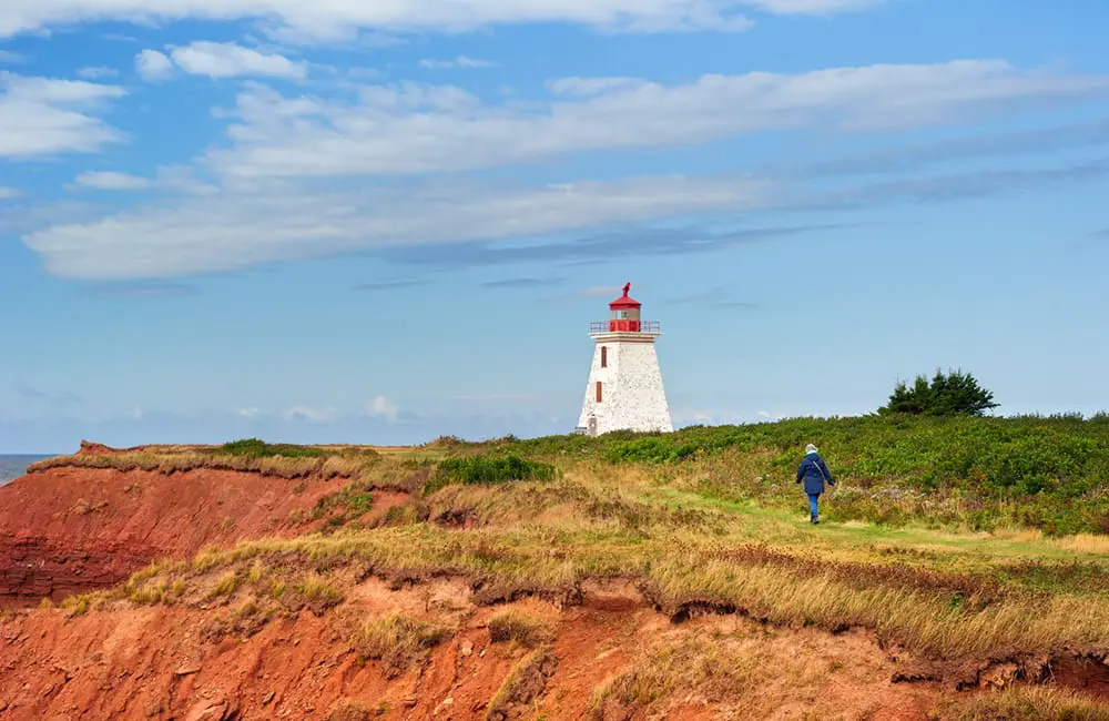 Atlantic Canada in autumn: 4 East Coast provinces with diverse cultures, sea-to-table flavours & alluring nature 9 Person walking towards Cape Edgmont Lighthouse, Prince Edward Island. Image: Sander Meurs
