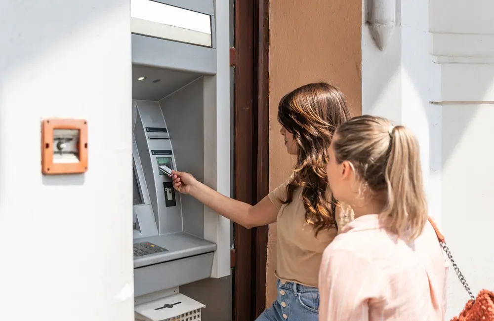 1 in 4 Aussies are taking 3 or more holidays in 2025 as travel intent surges: study 2 Two female tourists using at ATM – travel money card concept