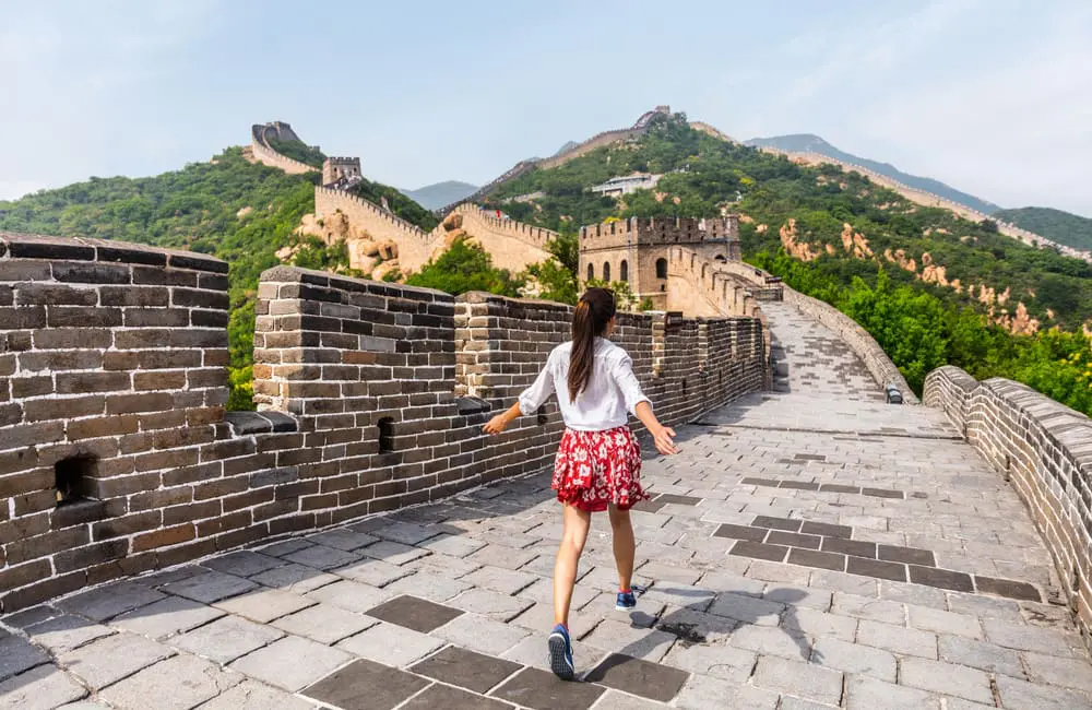 When life gives you $100K to spend, 13% of Aussies say "Book the trip!" 2 Woman running at Great Wall of China. $100K to spend
