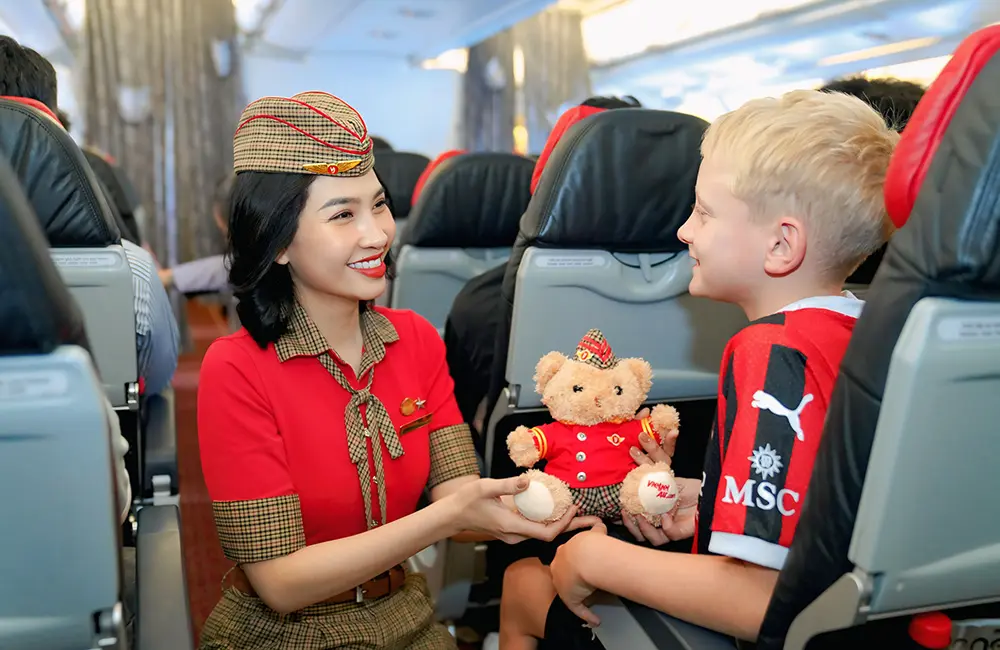 Vietjet drops Australia–Vietnam one-way fares from $199 plus bag perks & gift packs 1 A Vietjet flight attendant hands a branded teddybear to a boy in the aircraft cabin