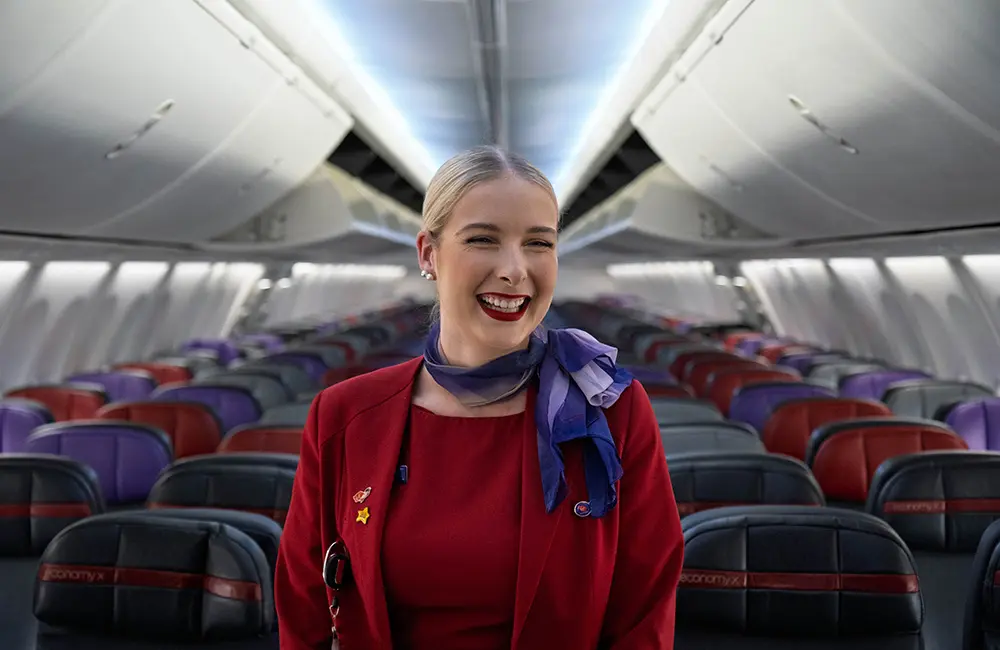 Interview: Virgin Velocity CEO Nick Rohrlach reveals how Velocity is giving travellers, and agents, the edge 2 Smiling blonde Virgin Australia flight attendant in empty cabin