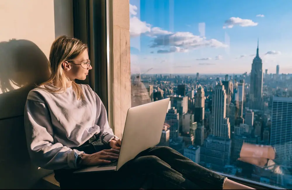 ATO targets bleisure trips: Corporate Traveller warns Aussies to tread carefully this tax season 4 Bleisure traveller in NYC hotel looking out window at city skyline. Image: Shutterstock
