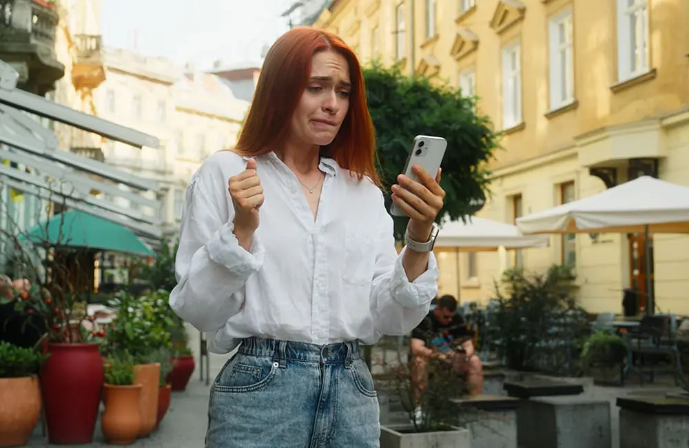 Most Aussies disappointed with social media travel recommendations IRL: study 1 Female traveller looking at smartphone with apprehensive look in European city – disappointed by social media travel reccs. Image: Shutterstock