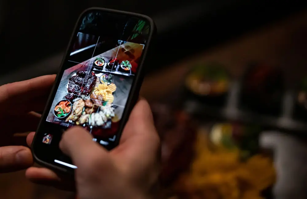 Most Aussies disappointed with social media travel recommendations IRL: study 2 Close-up of male hand holding a smartphone and taking a photo of food – social media travel reccs