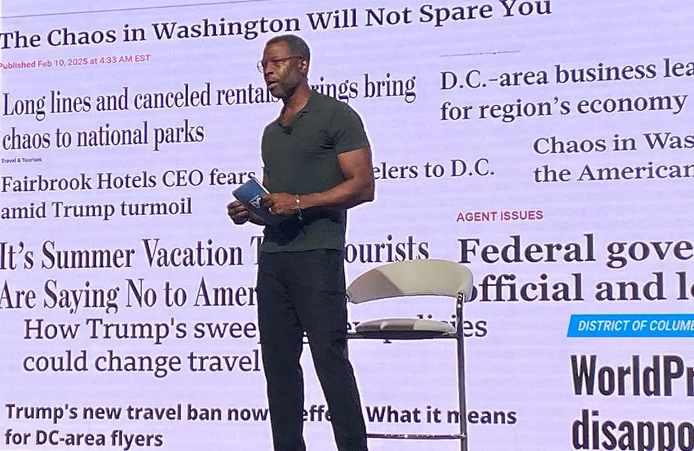Destination DC boss: Why the travel industry should focus on the positive experiences that the USA delivers 1 Destination DC President & CEO Elliott Ferguson against a slide backdrop of black-and-white newspaper headlines at IPW25. Image: Cassie Tannenberg