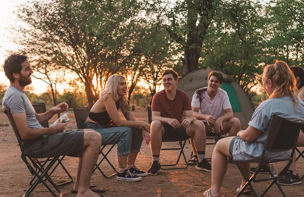 Intrepid reveals second 'Uncharted' mystery trip after 1K applicants applied for first round 1 Intrepid Travel group sitting on chairs at campsite in Africa – Intrepid Travel Uncharted Expedition 2026