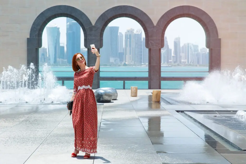 DFAT raises travel alert level for popular stopover for Australians 1 Girl in Doha against the blue sea. A tourist makes a selfie.