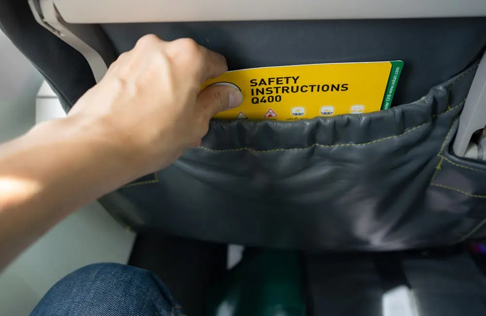 Ewww! Ex-flight attendants reveal the dirtiest places on planes & most unhygienic passenger practices 1 Male hand reaching for safety instructions in aircraft seatback pocket – dirtiest places on planes. Image: Shutterstock