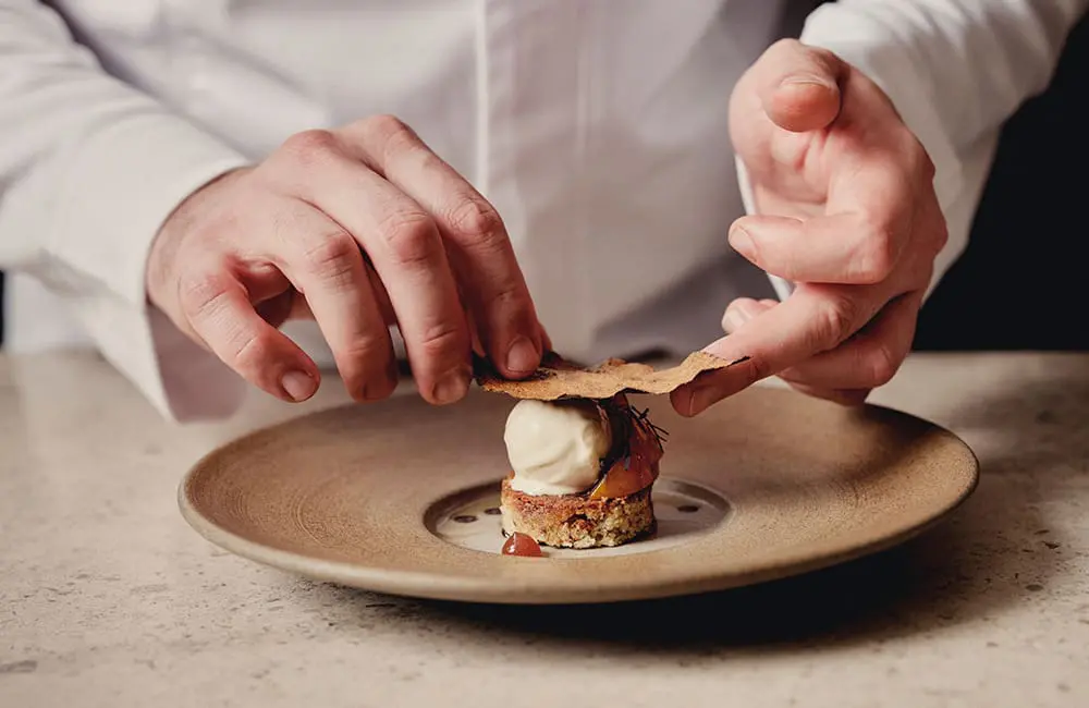 Belmond’s The Britannic Explorer rolls out as England & Wales' first-ever luxury sleeper train 3 Close-up of chef's hand plating a meal. Image: Belmond