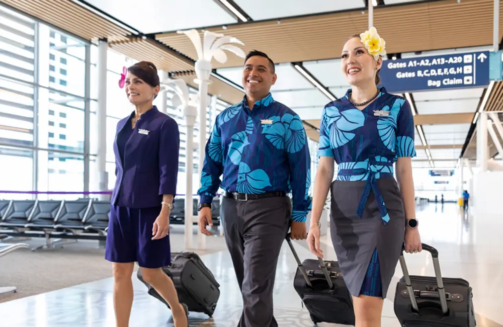 Hawaiian Airlines flight attendants with luggage walking through Mauka concourse at Honolulu Airport