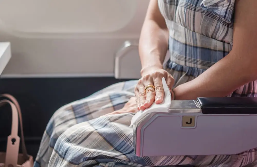 Ewww! Ex-flight attendants reveal the dirtiest places on planes & most unhygienic passenger practices 2 Female passengers wipes down seatrest – dirtiest places on planes. Image: Shutterstock