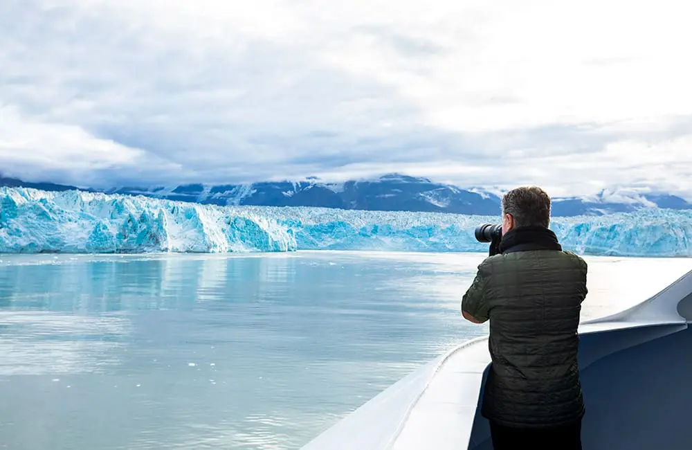 RSSC sees single biggest booking day for latest ultra-luxury ship; launches 234 new cruises for 2027-28 4 Man with camera pointed at Hubbard Glacier in Alaska on RSSC cruise.
