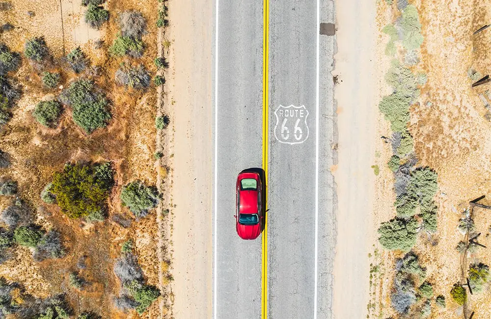 Open roads & borders: How to fast-track US entry plus new California road trips guide 4 Aerial view of red sedan car on Route 66 in California. Image: David Collier