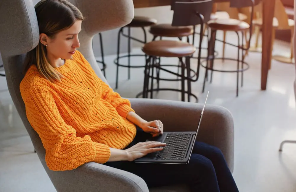 Work hard, holiday harder: 1 in 3 Aussie bosses now approve workations 2 Woman sitting on chair in hotel lobby using laptop – workations trend. Image: Shutterstock