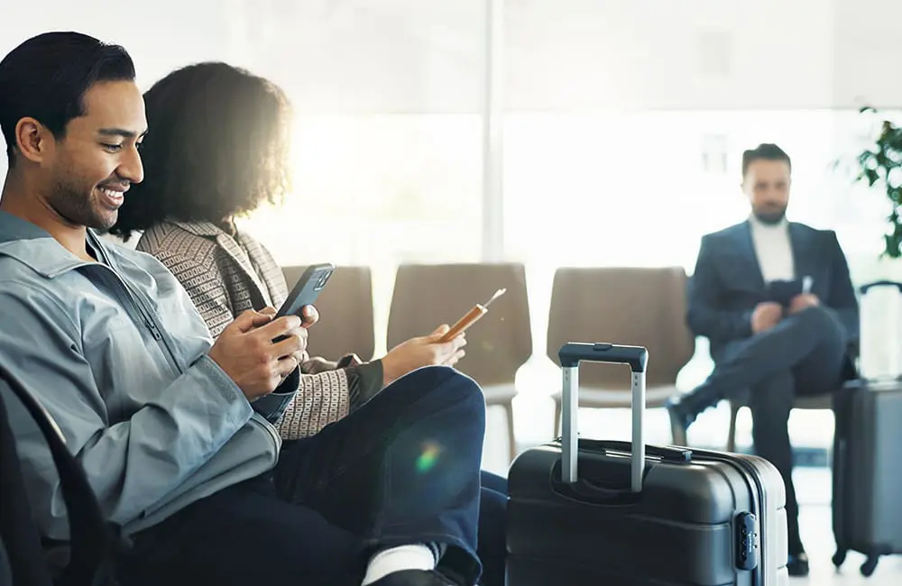 3 in 10 Aussies now use AI to book holidays with sharp uptake by this surprising source 3 Travellers in airport with smartphones – use AI to book holidays