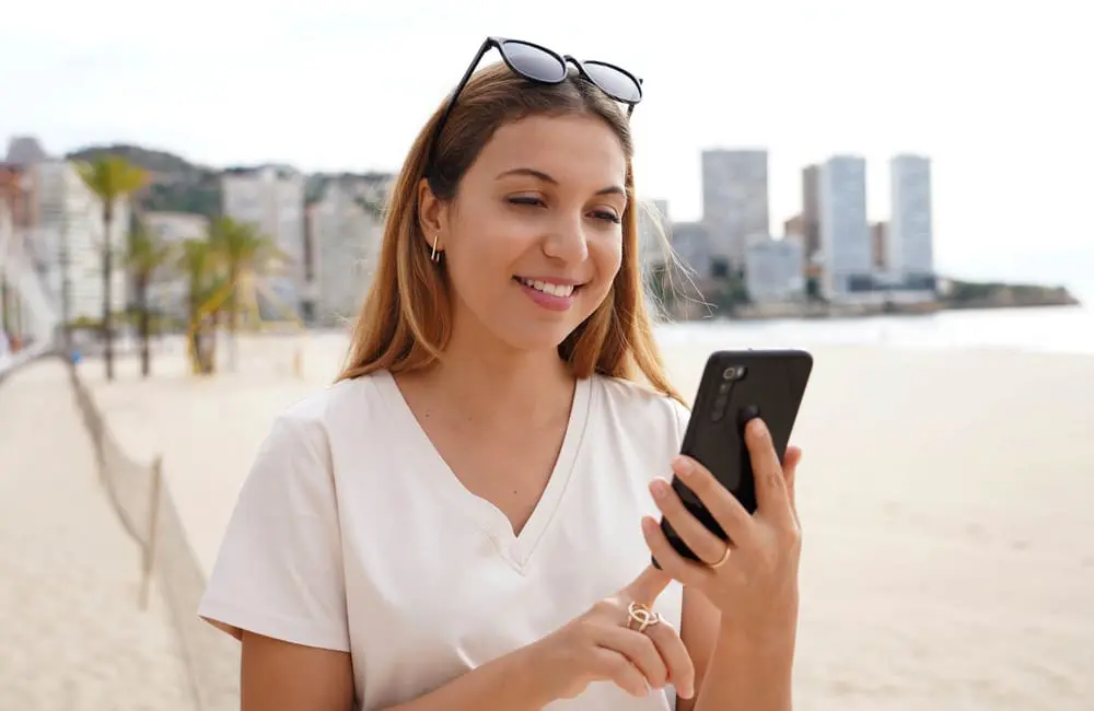 This APAC capital ranks as world’s best workation city for bleisure travellers in 2025 2 Female on smartphone in Rio with skyscrapers and beach in background – world's best workation cities. Image: Shutterstock