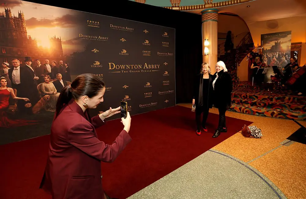 Set-jetting in style: Viking spotlights real-life Downton Abbey castle connection at exclusive Australian film premieres 5 Woman takes a photo of two women at the Viking Melbourne film premiere.