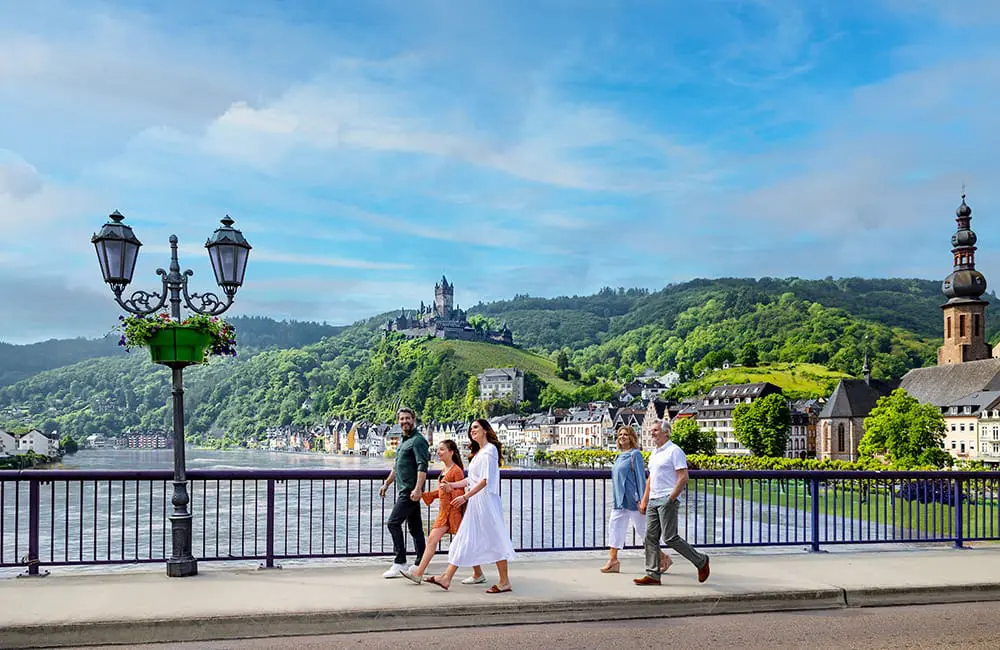 Beyond the banks: How AmaWaterways is redefining European river cruising through culture and connection 1 Multigenerational family walking together in Cochem with Reichsburg Castle on Moselle River in Germany.