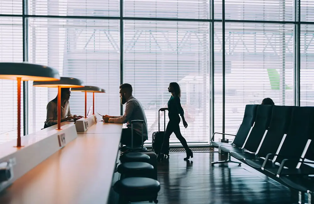 From points to perks: Expedia TAAP Rewards lands in Australia to boost booking bonuses 2 Female traveller wheeling luggage through airport with other passengers seated at desk. Image: EyeEm