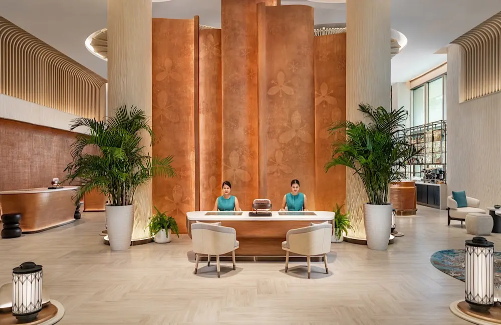Staff welcome guests in a lobby designed as an open social space under the sugar palm canopy.