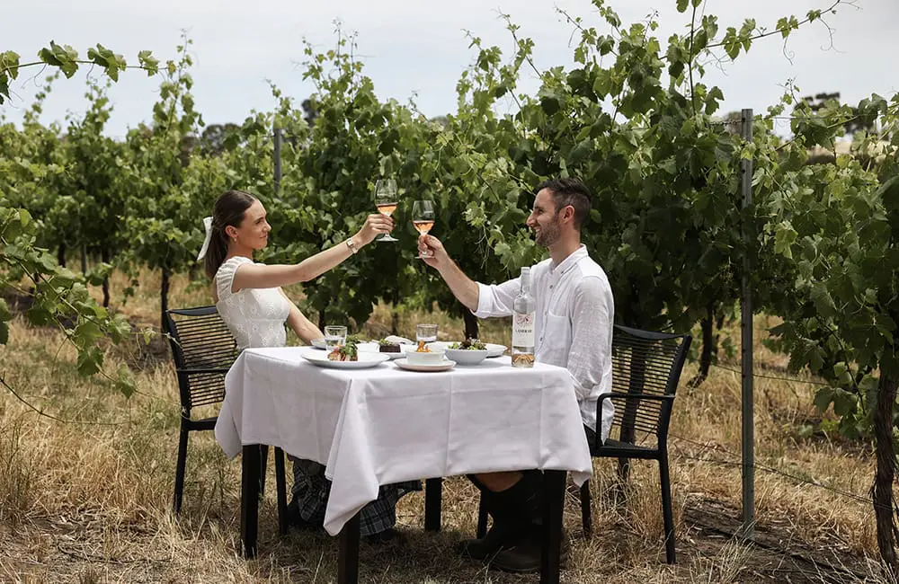 Revealed: The top Aussie travel experiences that stole the spotlight in 2025 2 Couple wine tasting with meal in vineyard in Australia - top Australian travel experiences of 2025
