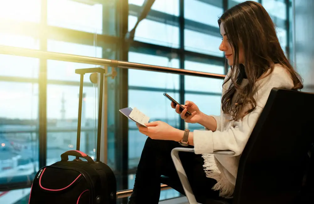 Female business traveller using smartphone at airport