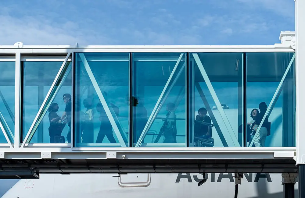 Korean Amway delegates on a Cairns Airport walkway with Asiana Airlines jet in background.