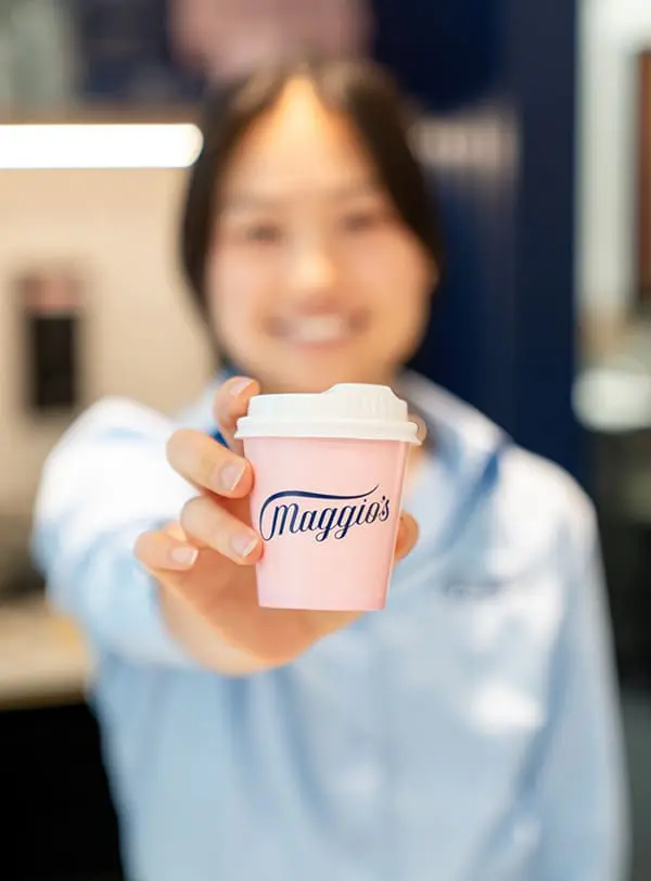 First stage of new T3 dining precinct opens as Sydney Airport predicts record festive season 1 Maggio's staff member holding out coffee cup with branding at the new Sydney Airport T3 cafe.
