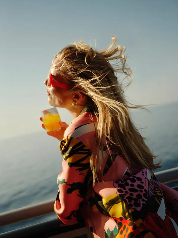 Virgin Voyages just launched a game-changing Status Match offer – are you eligible? 1 Woman with drink on Virgin Voyages cruise ship deck.