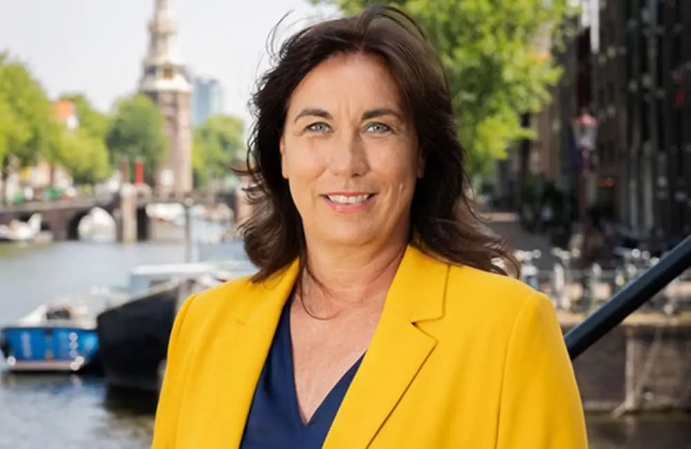 City of Amsterdam Deputy Mayor Hester van Buren standing in front of a canal.