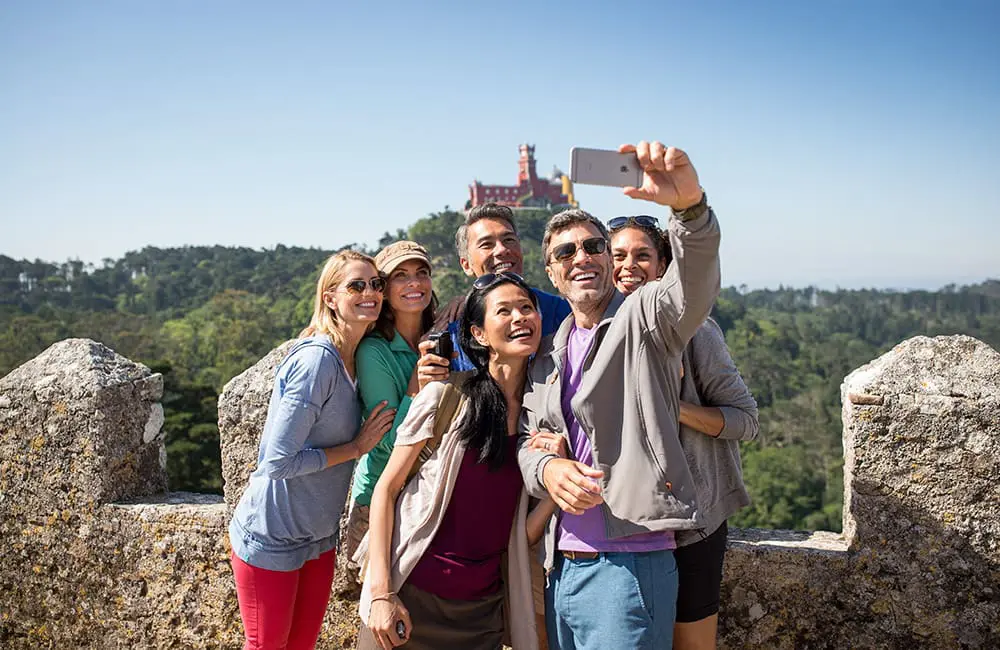 Globus Small Group Discovery tour group take a selfie in front of a European castle.