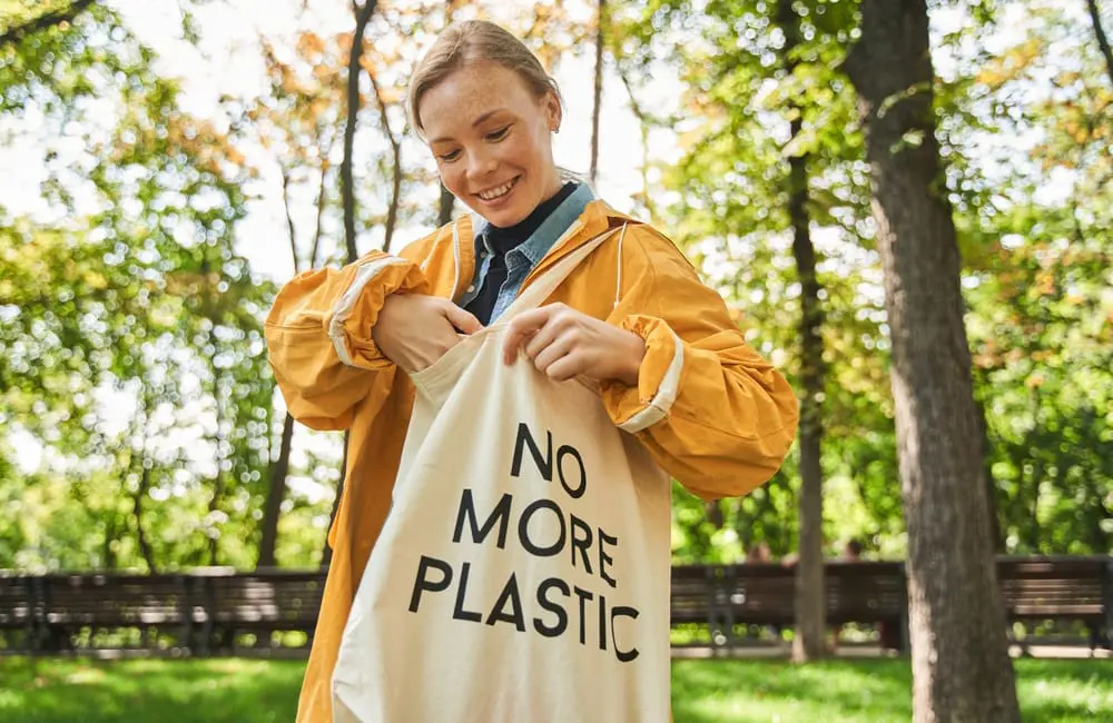Holiday mode activated? Why we forget to pack our green habits and how travel can close the gap 1 Female shopper with reusable calico bag with the words 'No More Plastic' – holiday mode sustainability