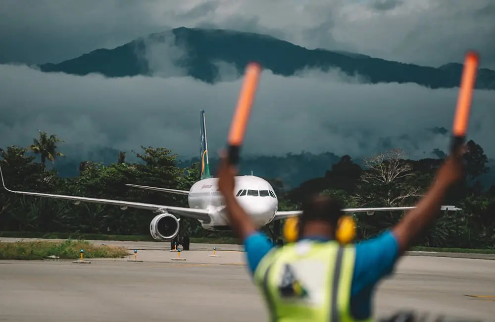 Solomon Airlines ground crew with aircraft on airport tarmac.