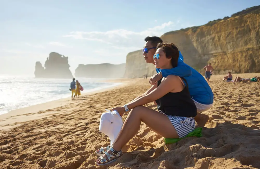 Asian tourists on beach at Gibson Steps on the Great Ocean Road in Victoria, Australia. Australian tourism forecast